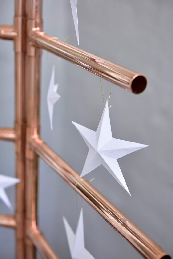 Paper stars hung from stylised Christmas tree hand-made from copper piping