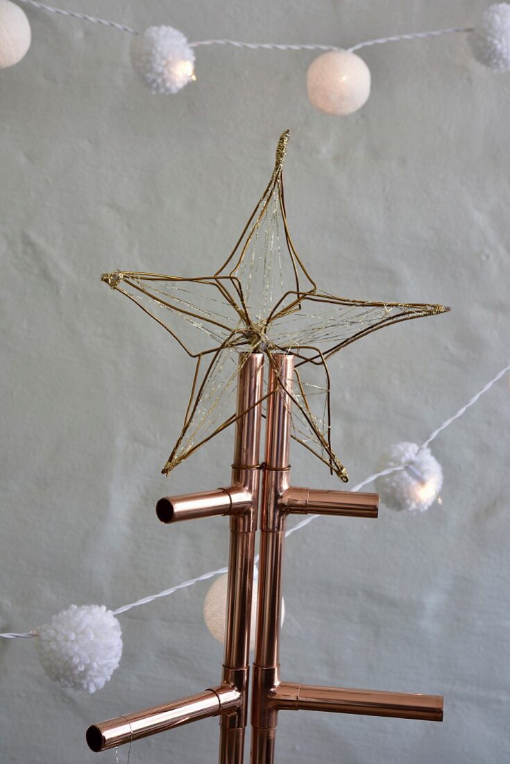 Goldener Stern aus Draht auf einem Weihnachtsbaum aus Kupferrohr