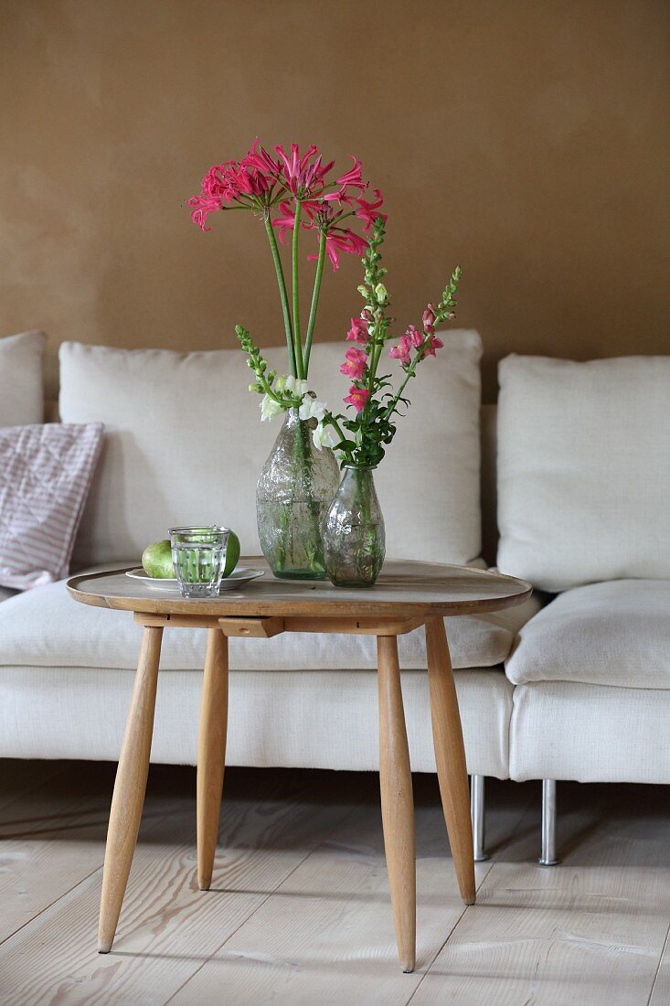 Schmucklilie und Löwenmäulchen auf rundem Holztisch im Wohnzimmer