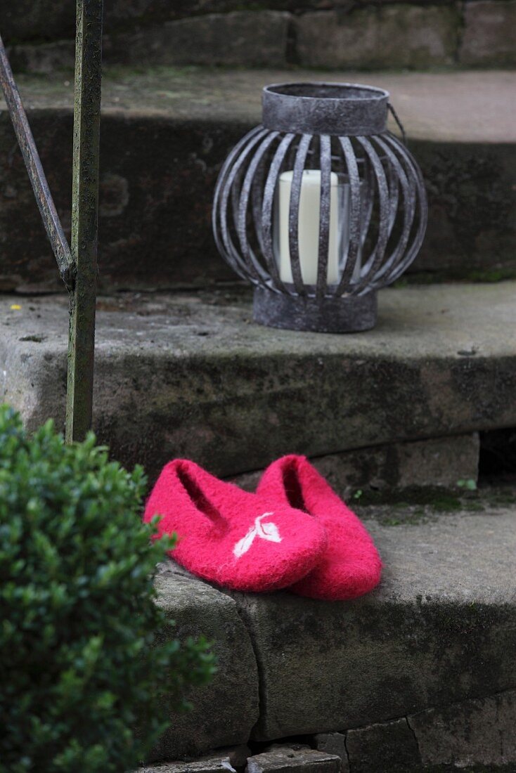 Pinkfarbene, selbstgefilzte Pantoffeln auf Vintage Steintreppe mit Windlicht