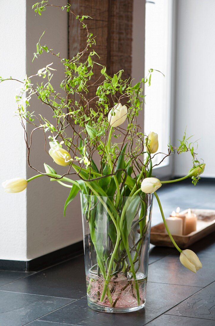 Glass vase of tulips on floor