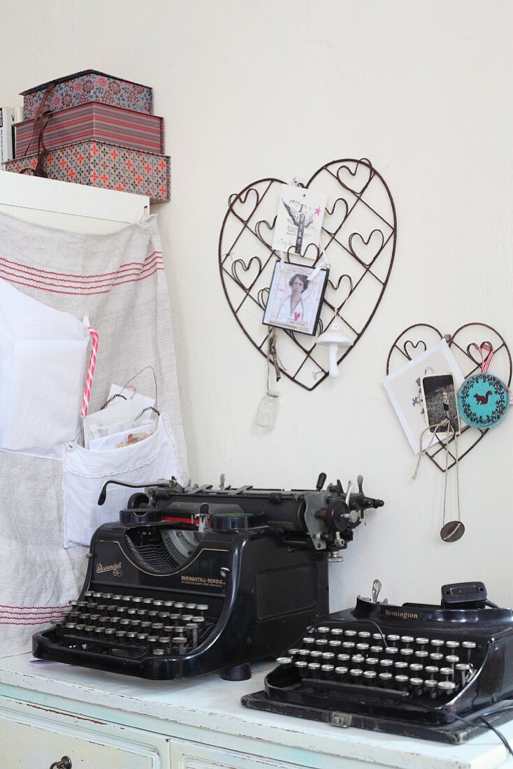 Nostalgische schwarze Schreibmaschinen vor aufgehängten, dekorierten Drahtherzen
