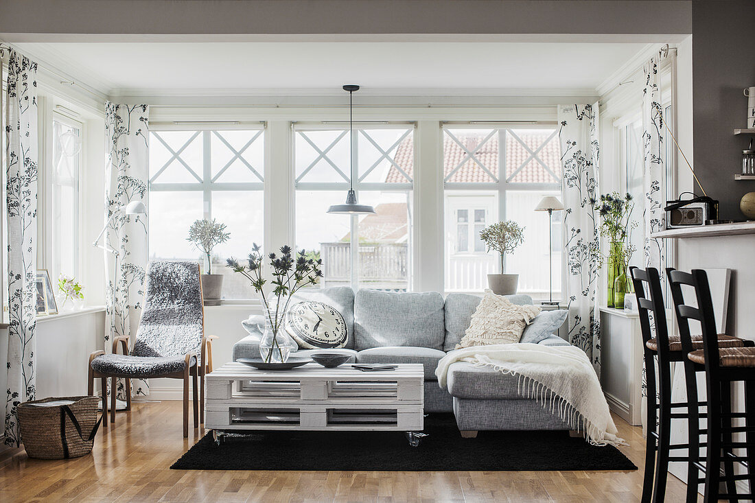 Wohnzimmer im Skandinavischen Stil mit grauem Sofa und Palettentisch