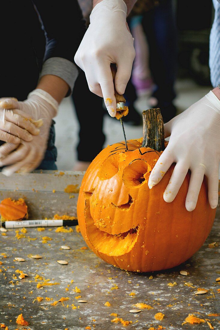 Halloweengesicht wird mit Säge in Kürbis geschnitzt