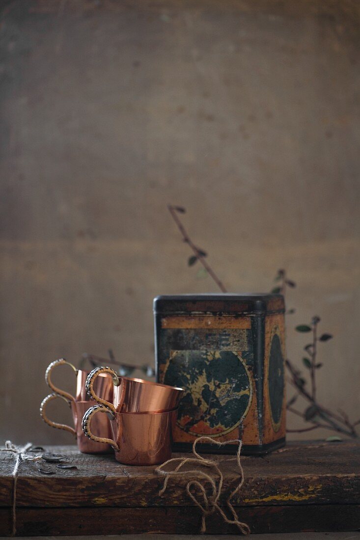 Copper cups and vintage tin on wooden table