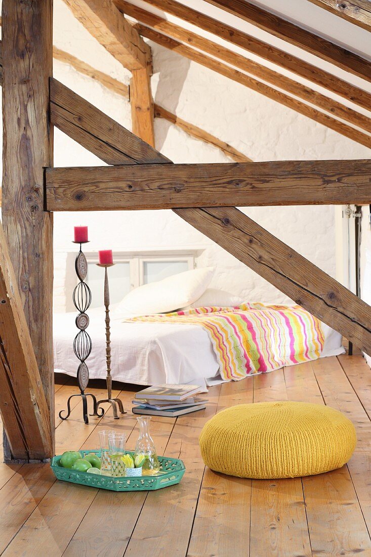 Yellow knitted pouffe in attic room of half-timbered house