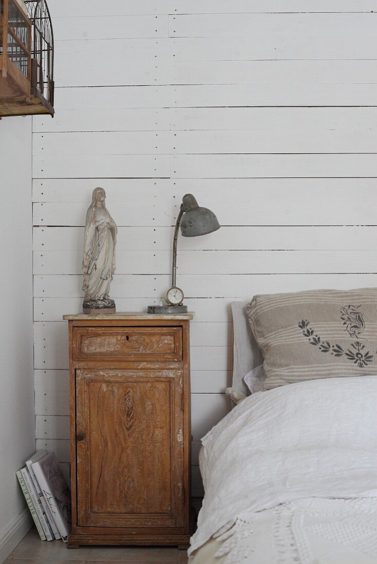 Wandverkleidung mit weiß gestrichenen Brettern hinter dem Bett