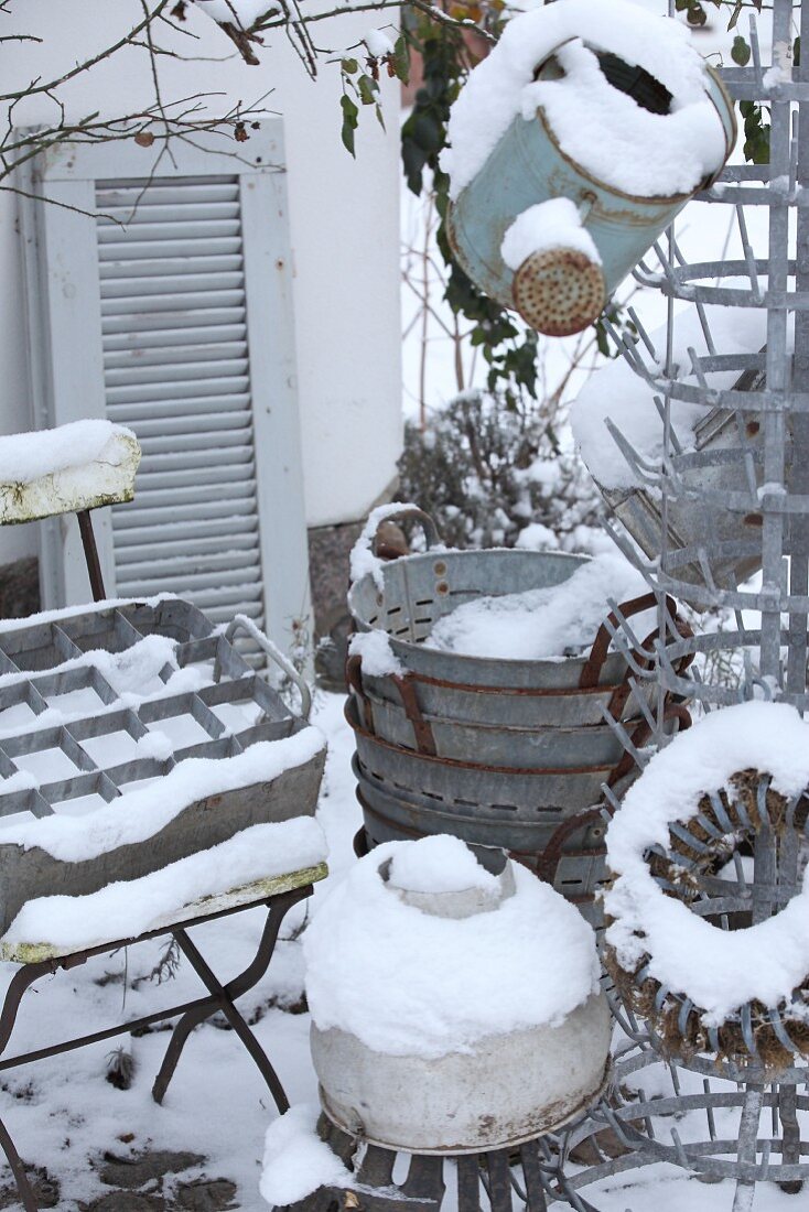Verschneite Sammlung von alten Zinkgegenständen im Garten