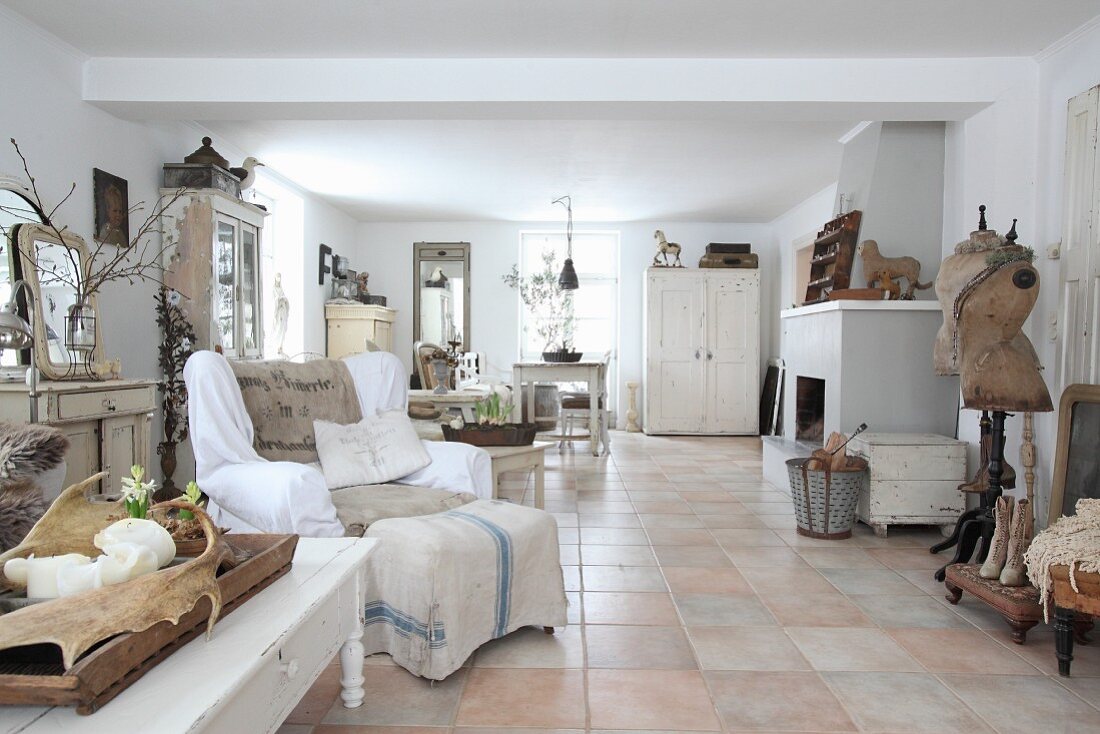 Terracotta-tiled floor and collection of vintage pieces in white interior