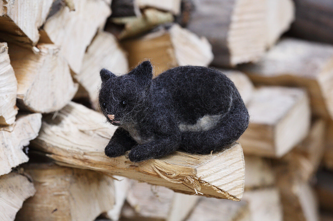 Hand-made, felted, woollen cat on log