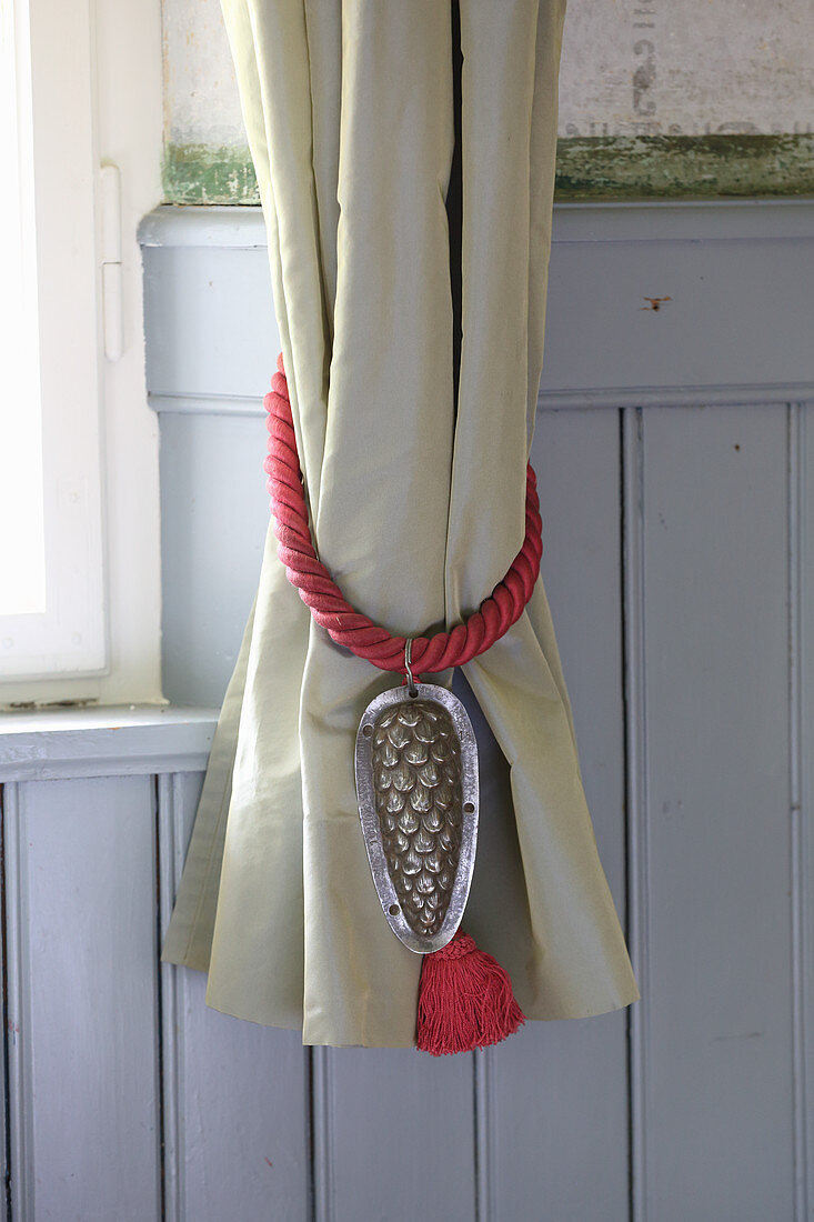 Curtain tie-back decorated with tassel and old cake tin