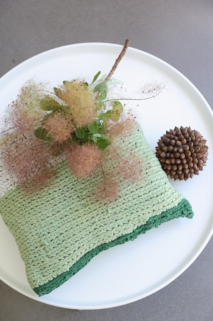 Green crocheted cushion made from T-shirt yarn on round coffee table