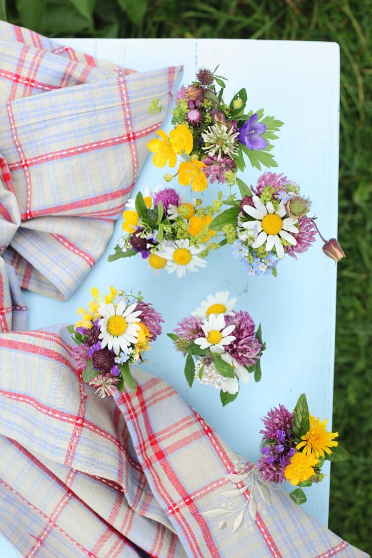 Posies of wildflowers and tartan cloth on pale blue table
