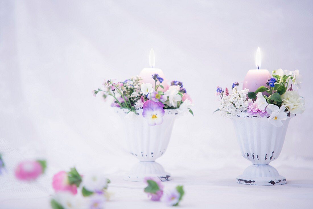 Romantische Blumengestecke mit brennenden Kerzen