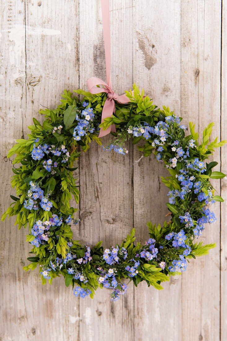 Spring wreath of box and forget-me-nots on board wall