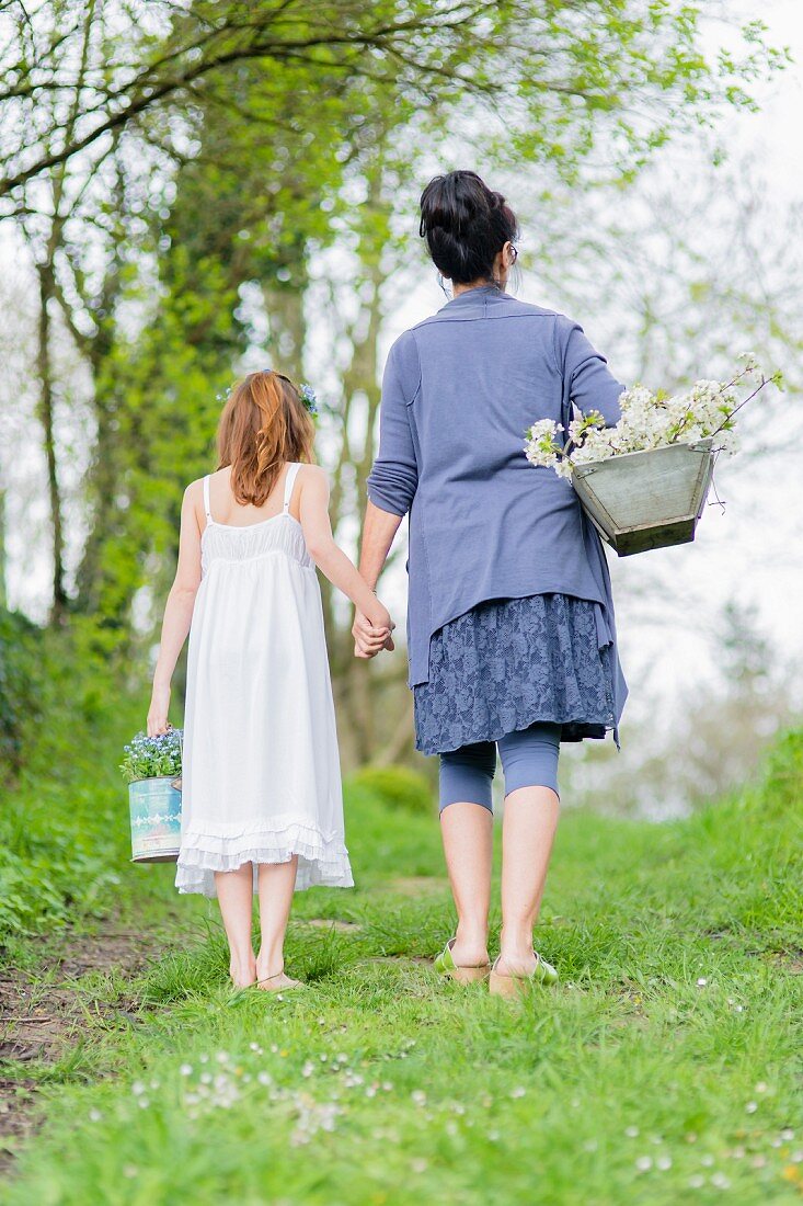 Mutter und Tochter Hand in Hand auf einer Frühlingswiese mit Blumenernte