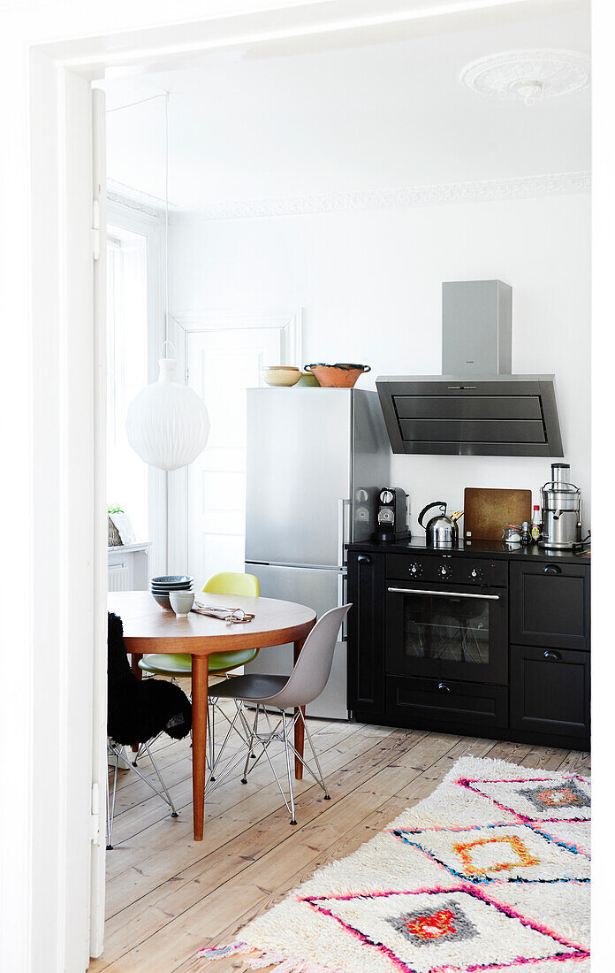 Black kitchen counter, fridge-freezer, dining table and chairs in kitchen in period building