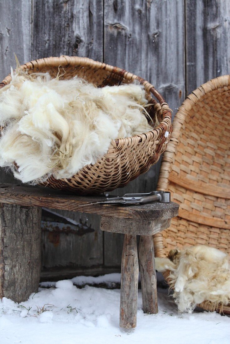 Uncombed wool on rustic stool in front of rustic board wall in snow