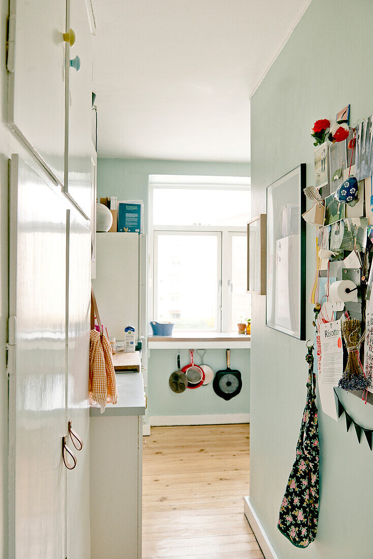 View past white fridge opposite pin board and into mint-green kitchen