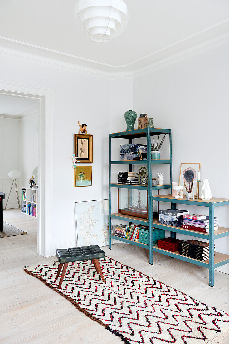 Rug with zigzag pattern in front of blue metal shelves in period interior