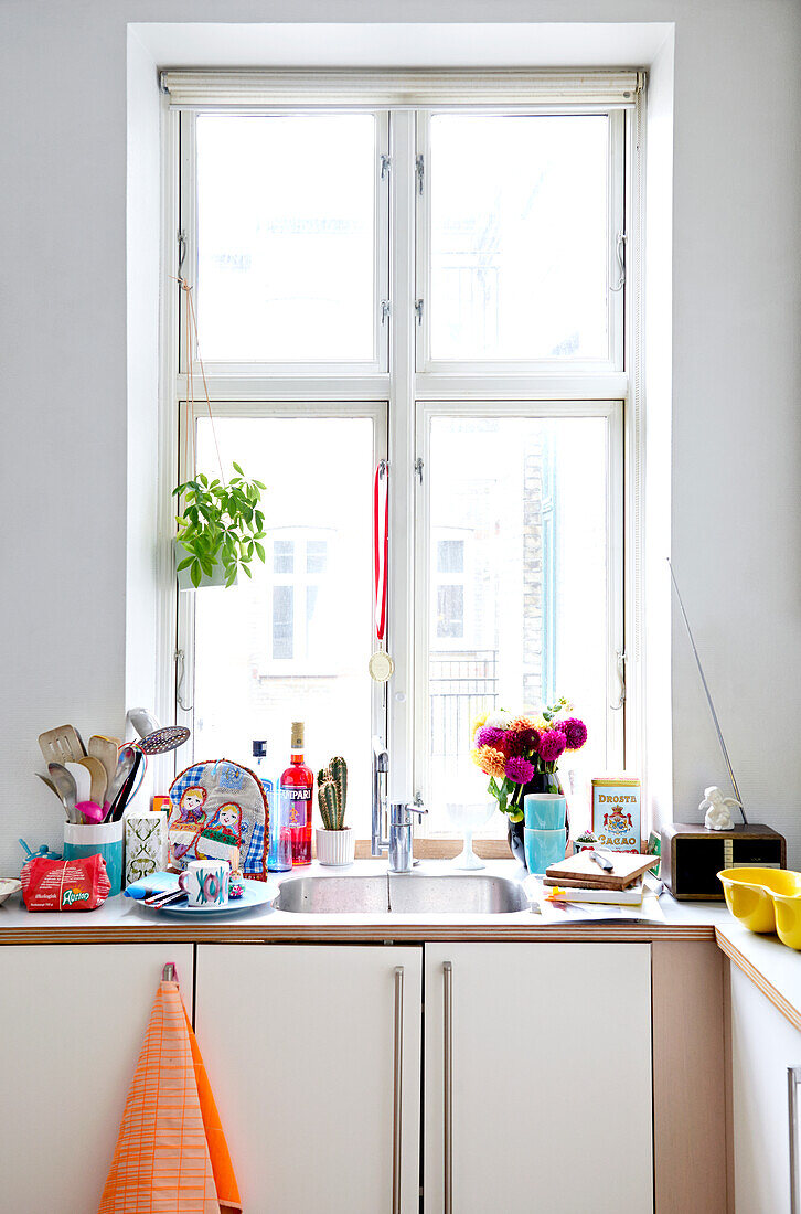 Colourful kitchen utensils around sink below window