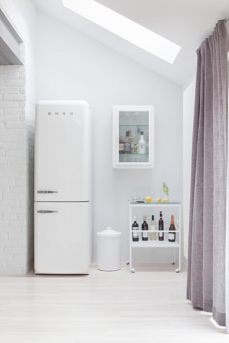 Retro-Kühlschrank in weißer Küche neben einem Servierwagen mit Bar