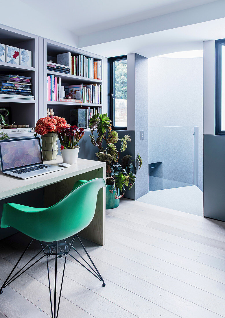 Arbeitszimmer mit Bücherregal, Schreibtisch und grünem Schalenstuhl