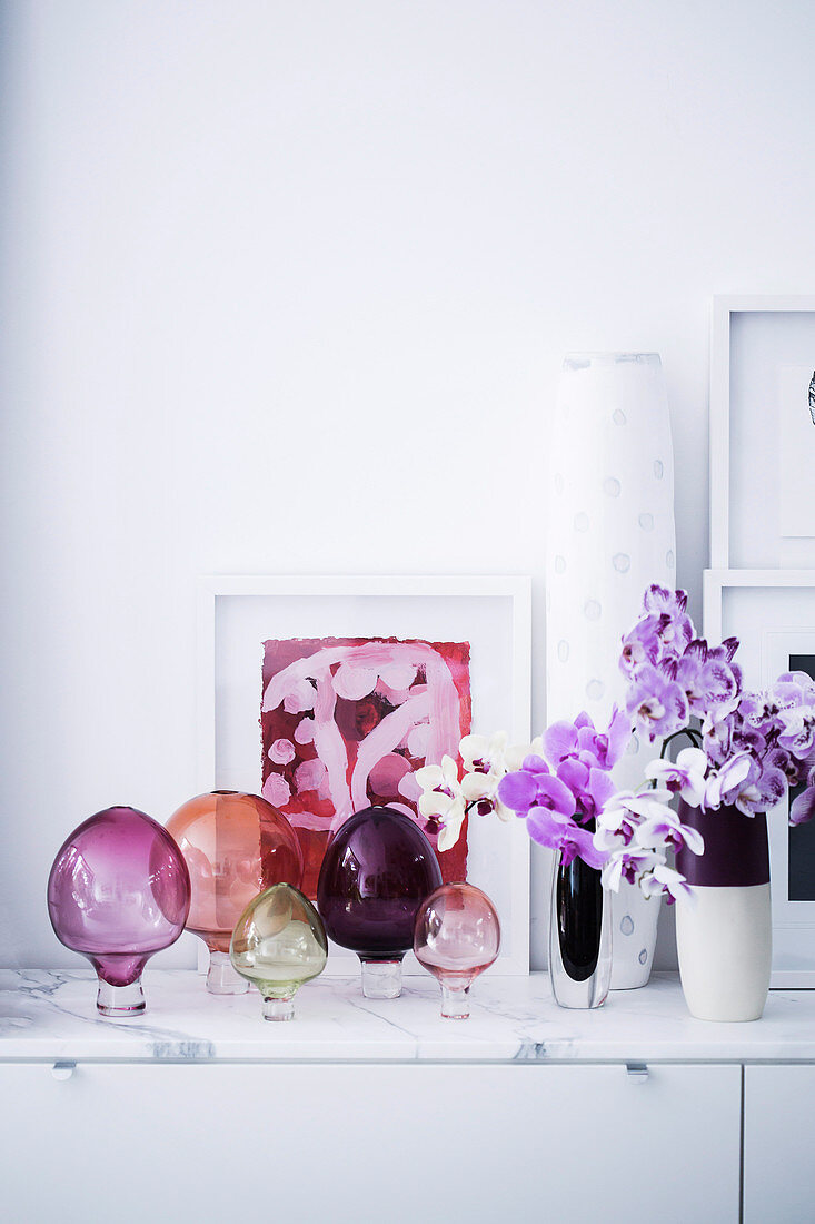 Colorful glass decoration and orchids on lowboard