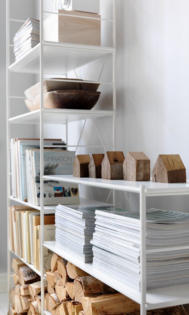 Books, stacked magazines and firewood on white shelves