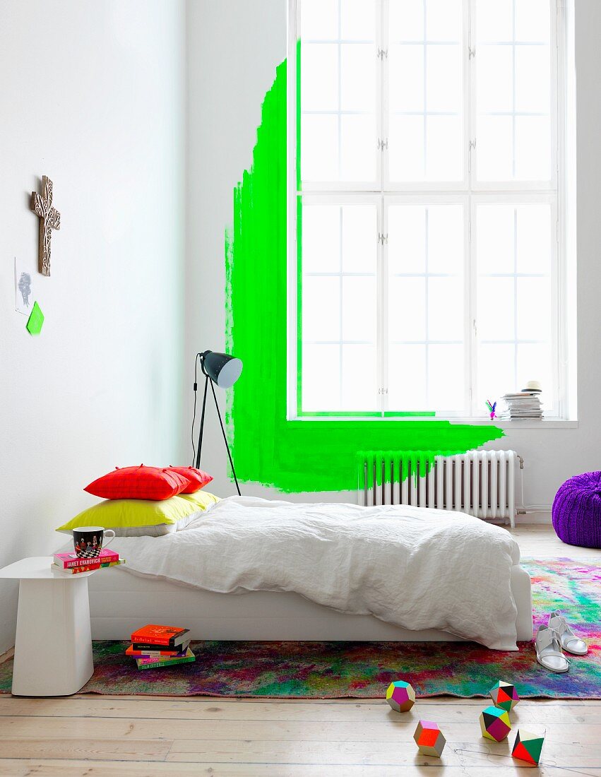 Neongrüne Wandgestaltung mit übermaltem Heizkörper vor hohem Altbaufenster im Schlafzimmer