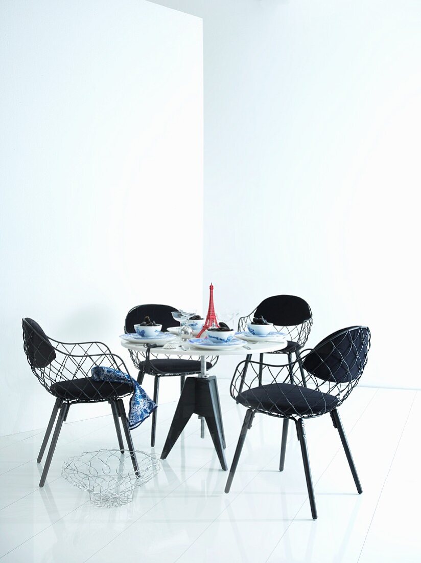 Essbereich mit rundem Tisch und schwarzen Stühlen, Tischdekoration mit rotem 'Eiffelturm-Modell'