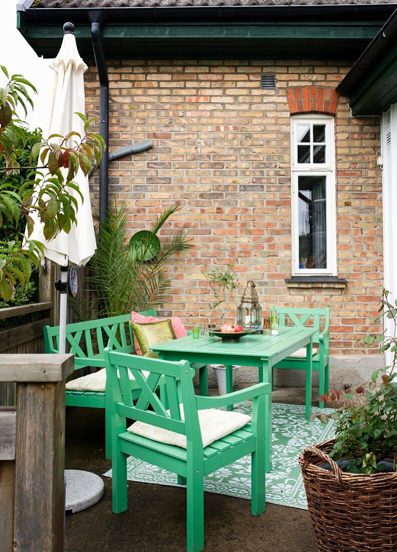 Green garden furniture on terrace outside brick house