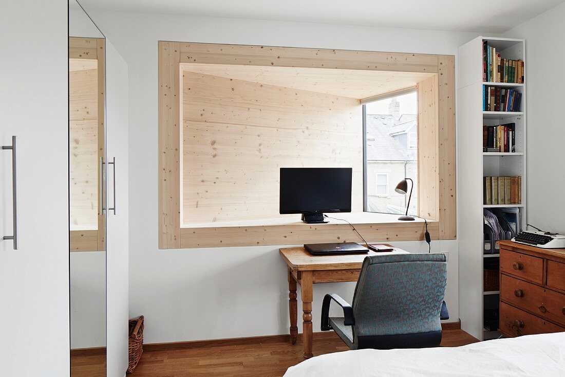 Home Office mit Computerbildschrim in holzverkleideter, abgeschrägter Fensterlaibung