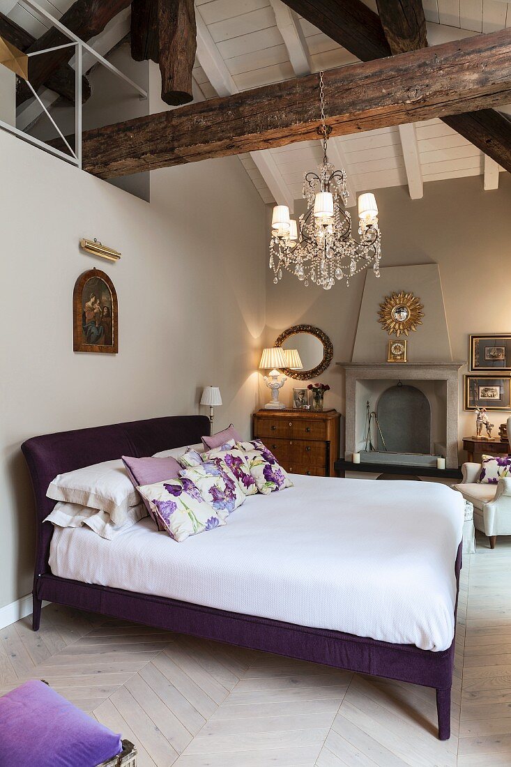 Bed with purple frame below exposed roof beams in bedroom