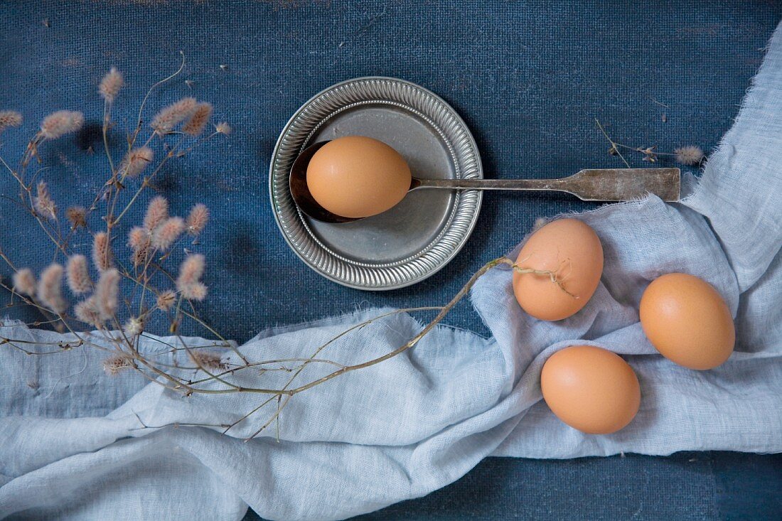 Hens' eggs and vintage spoon on blue fabrics