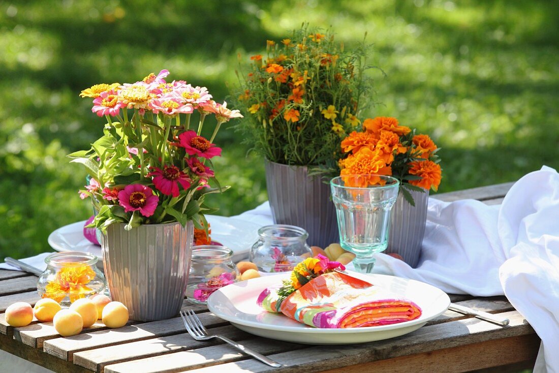 Farbenfrohe Tischdekoration mit Tagetes und Zinnias im Garten