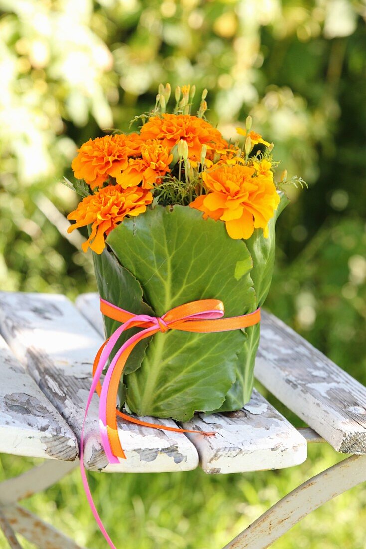 Tagetes wrapped in green leaves and ribbon