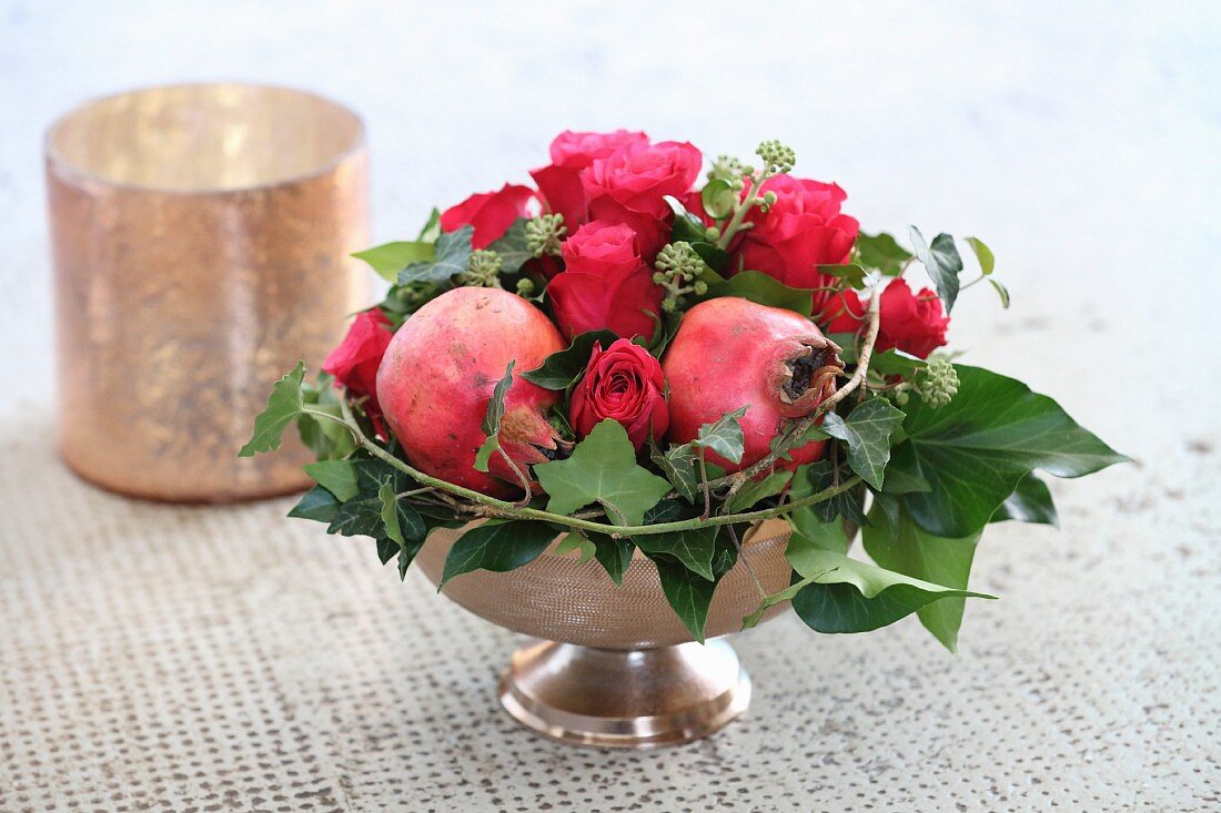 Festliches Weihnachtsgesteck mit Rosen, Granatäpfeln und Efeuranken
