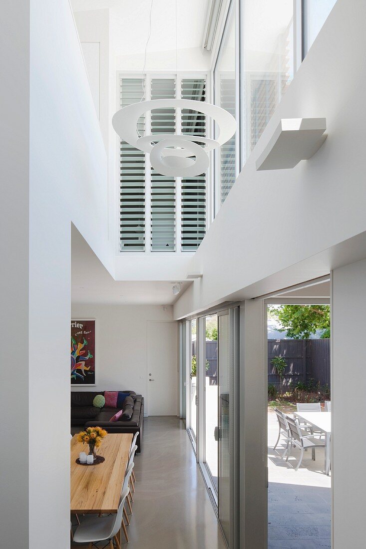 View from hallway into double-height living area with terrace windows