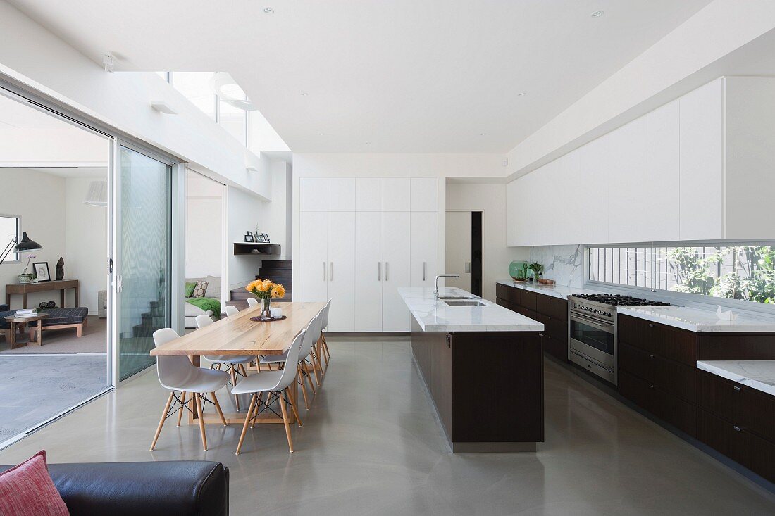 Dining area in open-plan, designer kitchen and view through open glass sliding door into living space