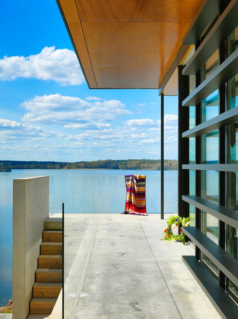 Terrace with concrete floor, glass balustrade and view of lake