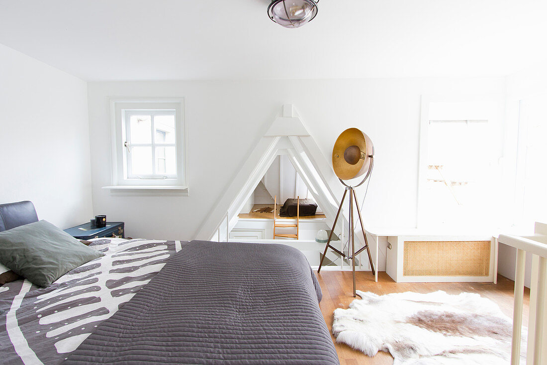 Schlafzimmer mit Doppelbett, Fotografenlampe und Tierfellteppich