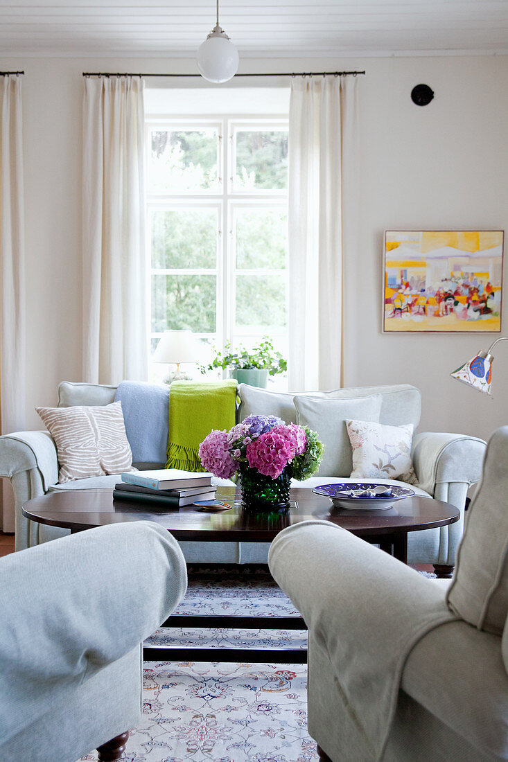 Vase of hydrangeas in living room with pale upholstered furnishings