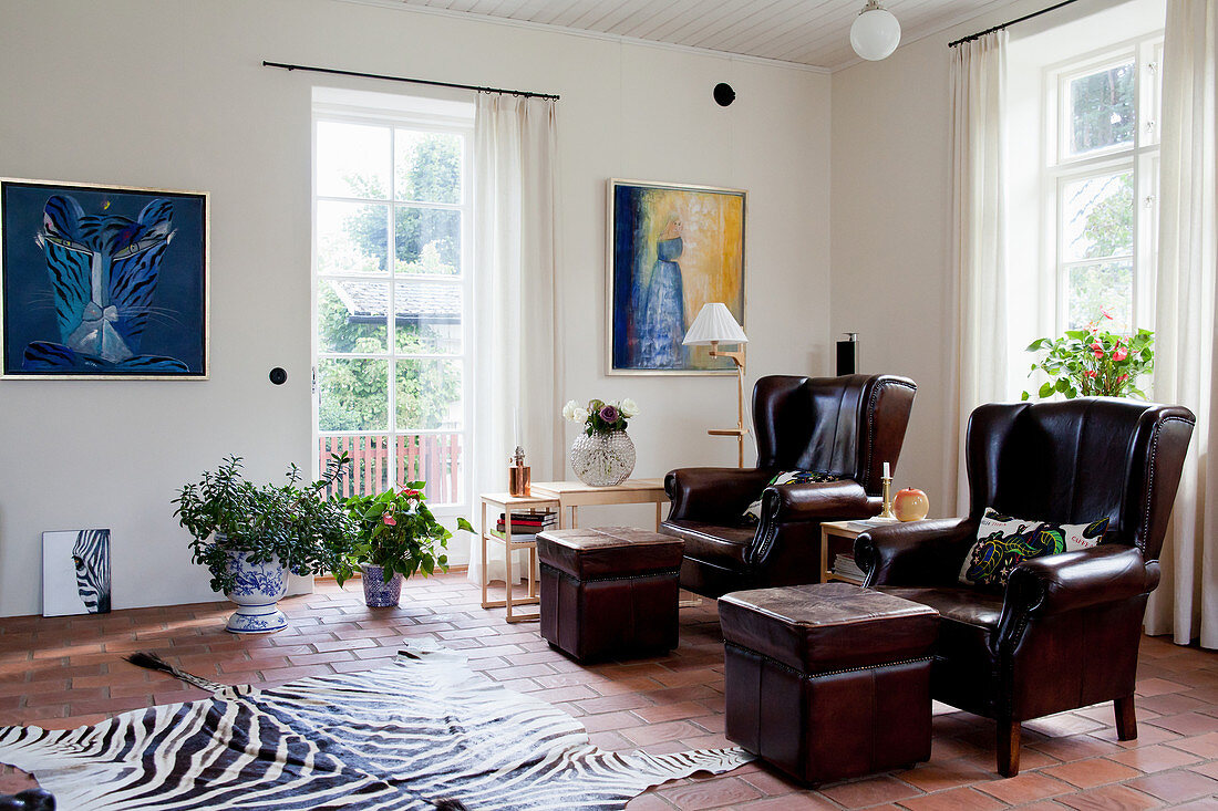 Two dark brown leather armchairs with footstools in living room