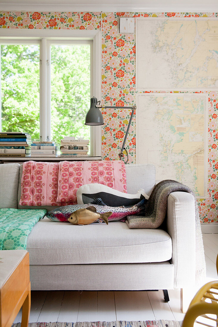 Fish-shaped cushions on sofa against floral wallpaper