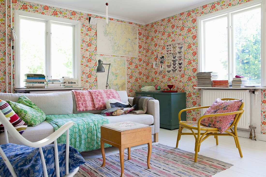Colourful, eclectic mixture of furniture in living room with floral wallpaper