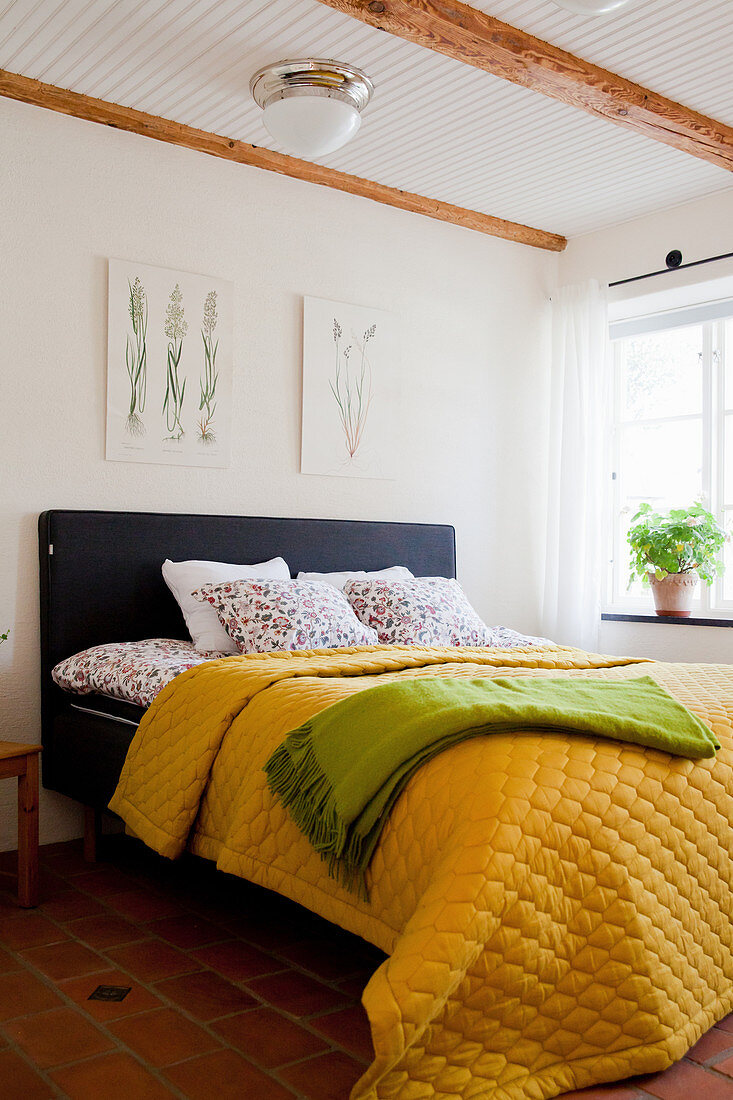 Yellow quilted bedspread on bed in rustic bedroom