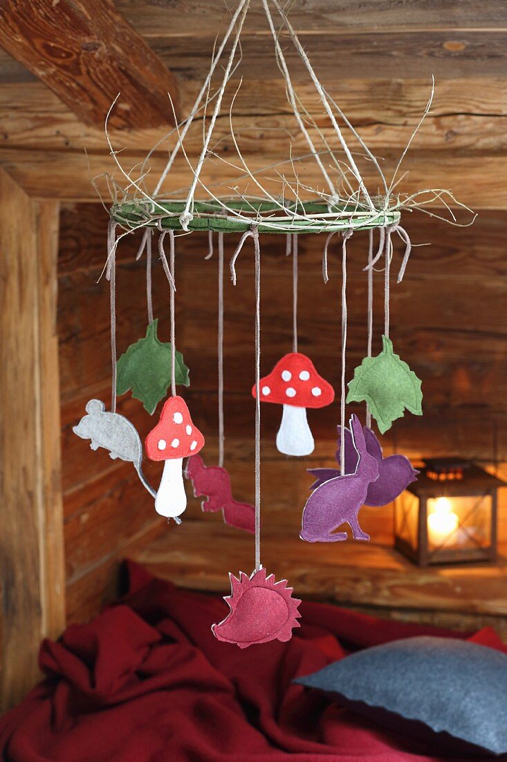 Various felt animals and toadstools hanging from hand-crafted mobile in cabin-style interior