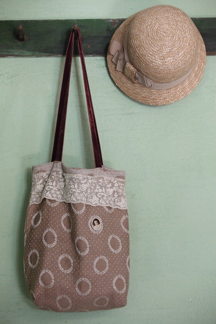 Bag with vintage-style embroidered medallion next to straw hat