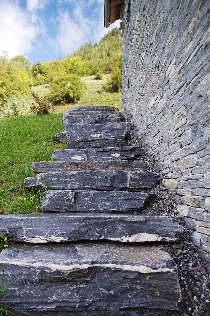 Treppe entlang der gemauerten Wand eines Steinhauses in den Bergen